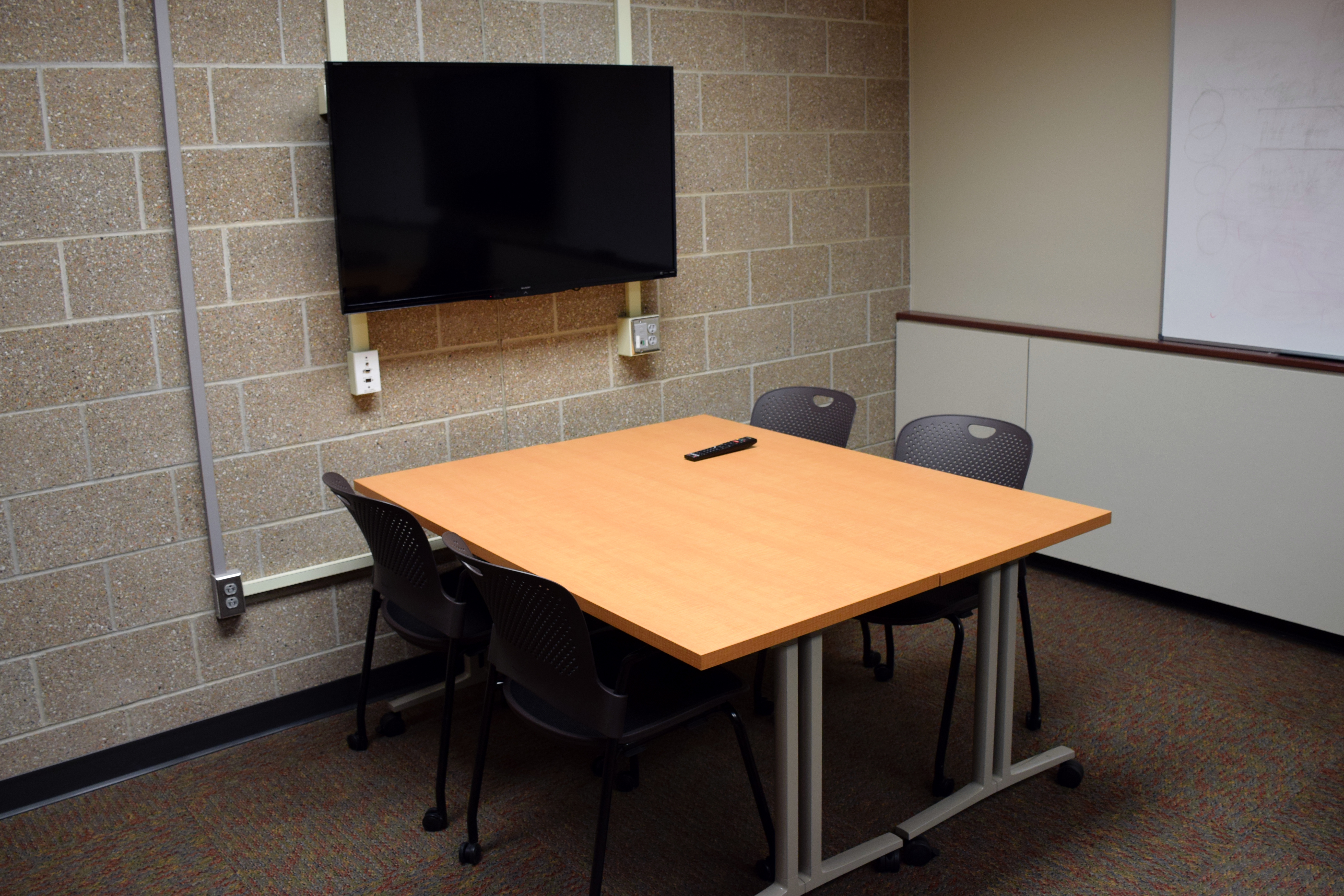 A huddle space in a conference room, with a small 4-person table and computer display